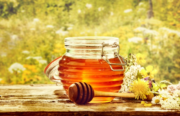 Bowl of honey with dipper in field of flowers