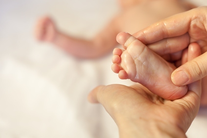 Mother makes massage for happy baby, apply oil on the foot, with white background